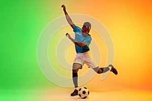 Male soccer, football player training in action isolated on gradient studio background in neon light