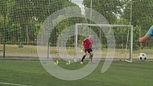 Male soccer goalie performing complex training, catching ball outdoors