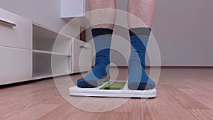 Male in socks with overweight standing on the scale