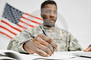 Male soldier hand holding pen and writing document.