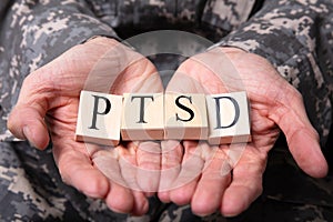 Male Soldier Holding Wooden Cubes With PTSD Text