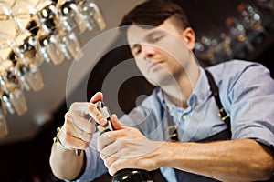 Male sommelier open wine bottle with corkscrew.