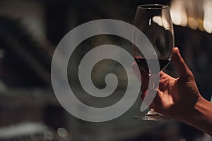 Male sommelier pouring holding wine in long-stemmed wineglasses.