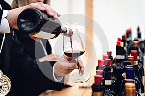 Male sommelier serving a glass of traditional red dolcetto wine