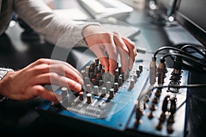 Male sound engineer hands on volume control panel