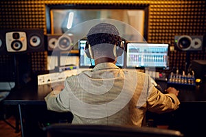 Male sound engineer at mixing consol, back view