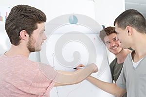 Male speaker in front whiteboard screen giving presentation