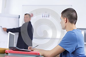 Male speaker in front whiteboard screen giving presentation