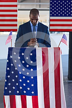 Male speaker standing with hands clasped at podium table