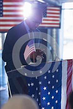 Male speaker standing with hands clasped at podium table