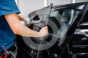 Male specialist applying car tinting film