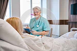 Male specialist holding tablet and talking to female patient