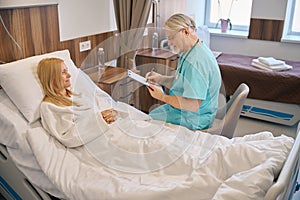 Male specialist holding tablet and talking to lady patient