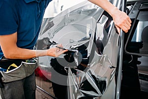 Male specialist with scissors, car tinting film