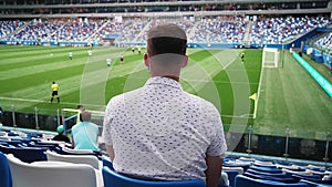Male spectator in a medical mask watching a football match at the stadium