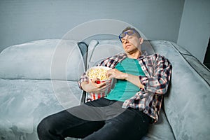 Male spectator sleeping on sofa in cinema hall