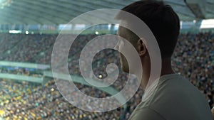Male spectator watching sport game at stadium, concentrated and agitated, worry