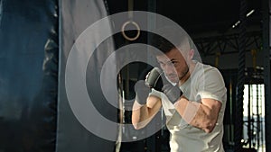 Male sportsman Caucasian man boxer training with punching bag boxing exercise at sport club motivated active guy fighter