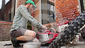 Male sportsman repairing his enduro motorcycle