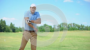 Male in sportswear playing golf, feeling elbow spasm, massaging painful area