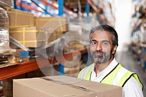 Male staff carrying cardboard boxes in warehouse