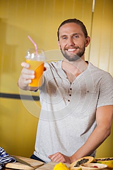 Male staff holding orange juice glass at organic section