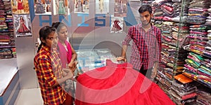 male staff showing clothes to the female customer at showroom in India
