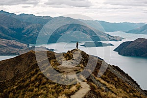 Male standing on a top of the mountain range with a sea in the background, Roys Peak Glendhu