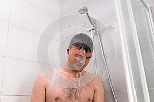 Male standing under flowing water in shower cabin