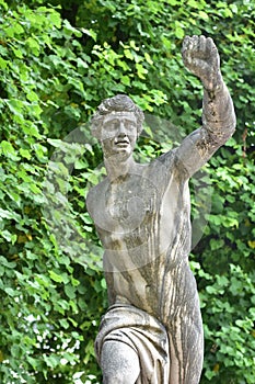 Male stone statue at hedges