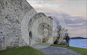 Male stood by the side of a lake next to a castle