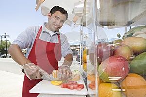 Male Street Vendor Chopping Fruits photo