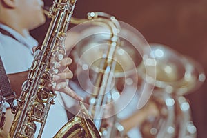 Male student with friends blow the saxophone with the band for performance on stage