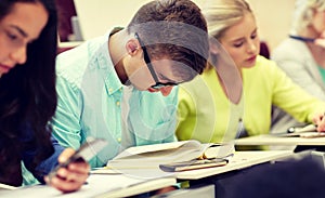 Male student in glasses reading book at lecture