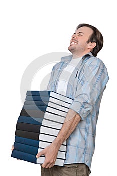 Male student holds heavy stack of books