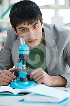 Male student in laboratory working with microscope