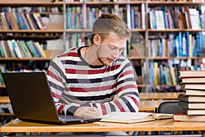 Masculino alumno computadora portátil el estudio en universidad biblioteca 