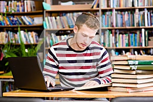 Male student with laptop studying in the university library photo