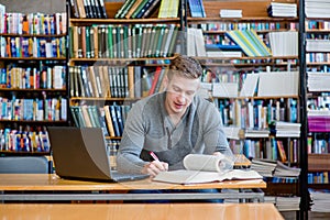 Masculino alumno computadora portátil el estudio en universidad biblioteca 