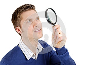 Male student looking through a magnifying glass