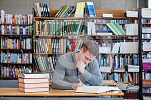 Male student with open book working in a library