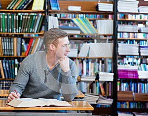 Male student with open book working in a library