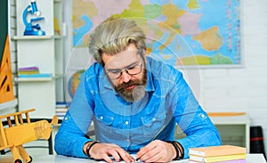 Male student preparing for exam. Teacher working at table in classroom. Test of knowledge. High school. Male student