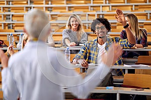 Male student raising the hand to answer the professor question at the lecture