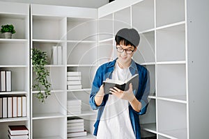 Male student taking notes from a book at library, Young asian sitting at desk doing assignments in college library