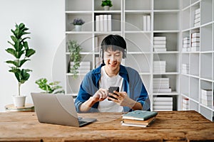 Male student taking notes from a book at library, Young asian sitting at desk doing assignments in college library