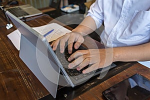 Male student wearing white shirt typing laptop keyboard