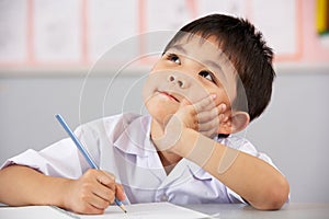 Male Student Working At Desk In Chinese School photo