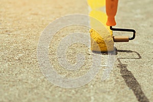 Male students use small paint rollers to paint yellow lines on the cement floor for Sepak Takraw