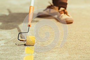 Male students use small paint rollers to paint yellow lines on the cement floor for Sepak Takraw